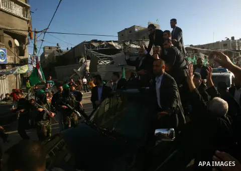 Hamas chief Khaled Meshaal, riding in a car with Palestinian prime minister in Gaza Strip Ismail Haniyeh, waves to the crowd upon his arrival in Gaza City December 7, 2012. Meshaal is making his first-ever visit to the G...