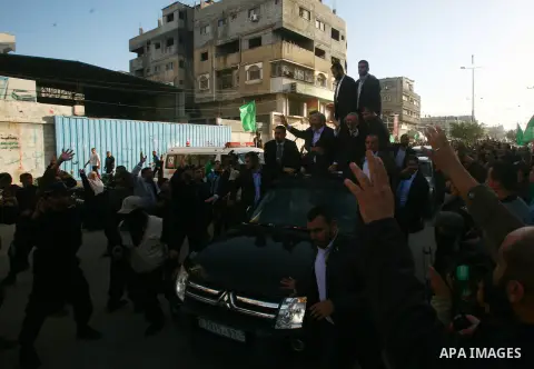 Hamas chief Khaled Meshaal, riding in a car with Palestinian prime minister in Gaza Strip Ismail Haniyeh, waves to the crowd upon his arrival in Gaza City December 7, 2012. Meshaal is making his first-ever visit to the G...