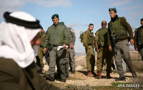 Israel soldiers stand guards as they prevent Palestinians from reaching their farming lands near the Jewish settlement of Sosia in the West Bank city of Hebron on December 7,2012. Israel intends to carry out extensive bu...