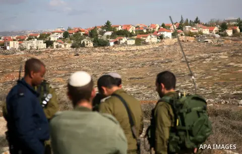 Israel soldiers stand guards as they prevent Palestinians from reaching their farming lands near the Jewish settlement of Sosia in the West Bank city of Hebron on December 7,2012. Israel intends to carry out extensive bu...