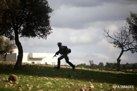 An Israeli soldier fires tear gas towards Palestinian protesters during clashes following a demonstration against the expropriation of Palestinian land by Israel in the West Bank village of Nabi Saleh on December 7, 2012...