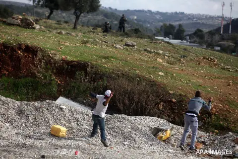 Palestinian protesters runs from tear gas during clashes following a demonstration against the expropriation of Palestinian land by Israel in the West Bank village of Nabi Saleh on December 7, 2012. Photo by Issam Rimawi