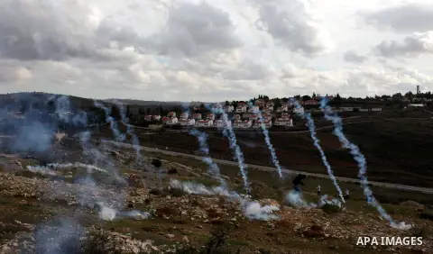 A Palestinian protester runs from tear gas during clashes following a demonstration against the expropriation of Palestinian land by Israel in the West Bank village of Nabi Saleh on December 7, 2012. Photo by Issam Rimaw...