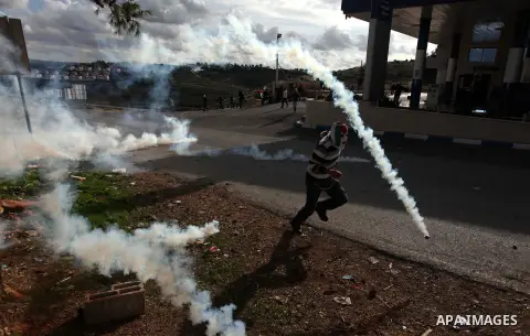 A Palestinian protester runs from tear gas during clashes following a demonstration against the expropriation of Palestinian land by Israel in the West Bank village of Nabi Saleh on December 7, 2012. Photo by Issam Rimaw...