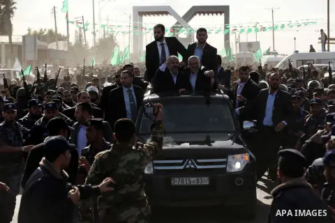 Hamas chief Khaled Meshaal waves to the crowd from his car beside senior Hamas leader Ismail Haniyeh at the Rafah Crossing, in southern Gaza Strip December 7, 2012. Meshaal ended decades of exile from Palestinian land on...