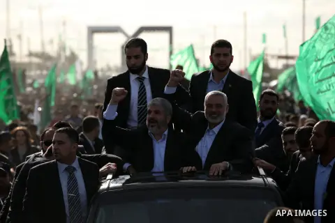 Hamas chief Khaled Meshaal waves to the crowd from his car beside senior Hamas leader Ismail Haniyeh at the Rafah Crossing, in southern Gaza Strip December 7, 2012. Meshaal ended decades of exile from Palestinian land on...