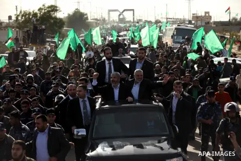 Hamas chief Khaled Meshaal waves to the crowd from his car beside senior Hamas leader Ismail Haniyeh at the Rafah Crossing, in southern Gaza Strip December 7, 2012. Meshaal ended decades of exile from Palestinian land on...
