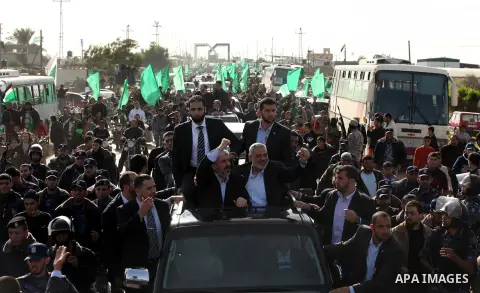 Hamas chief Khaled Meshaal waves to the crowd from his car beside senior Hamas leader Ismail Haniyeh at the Rafah Crossing, in southern Gaza Strip December 7, 2012. Meshaal ended decades of exile from Palestinian land on...