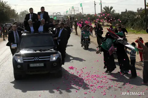 Hamas chief Khaled Meshaal waves to the crowd from his car beside senior Hamas leader Ismail Haniyeh at the Rafah Crossing, in southern Gaza Strip December 7, 2012. Meshaal ended decades of exile from Palestinian land on...