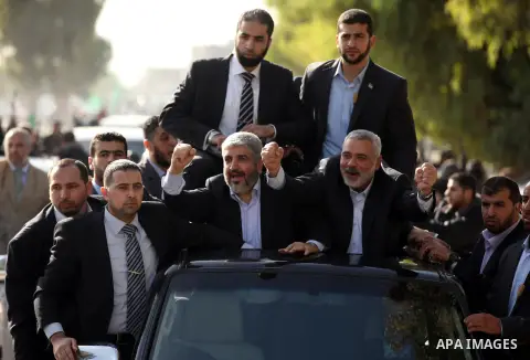 Hamas chief Khaled Meshaal waves to the crowd from his car beside senior Hamas leader Ismail Haniyeh at the Rafah Crossing, in southern Gaza Strip December 7, 2012. Meshaal ended decades of exile from Palestinian land on...