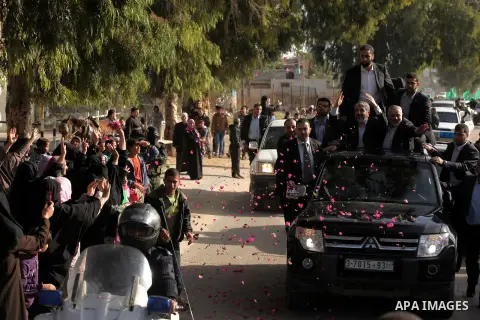 Hamas chief Khaled Meshaal waves to the crowd from his car beside senior Hamas leader Ismail Haniyeh at the Rafah Crossing, in southern Gaza Strip December 7, 2012. Meshaal ended decades of exile from Palestinian land on...