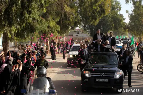 Hamas chief Khaled Meshaal waves to the crowd from his car beside senior Hamas leader Ismail Haniyeh at the Rafah Crossing, in southern Gaza Strip December 7, 2012. Meshaal ended decades of exile from Palestinian land on...