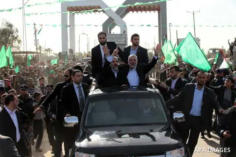 Hamas chief Khaled Meshaal waves to the crowd from his car beside senior Hamas leader Ismail Haniyeh at the Rafah Crossing, in southern Gaza Strip December 7, 2012. Meshaal ended decades of exile from Palestinian land on...