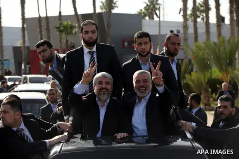 Hamas chief Khaled Meshaal waves to the crowd from his car beside senior Hamas leader Ismail Haniyeh at the Rafah Crossing, in southern Gaza Strip December 7, 2012. Meshaal ended decades of exile from Palestinian land on...