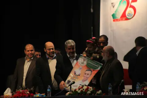 Hamas chief Khaled Meshaal, hold a protrait of a Palestinian prisoner during a meeting with the relatives of prisoners in Israeli jails in Gaza City December 9, 2012. Meshaal, in a defiant speech during his first ever vi...