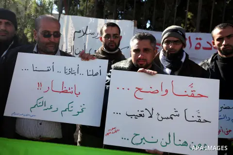 Palestinian teachers and graduates who were barred from employment by Ministry of Education, hold placards during a protest in front of Council of Ministers, in the West Bank city of Ramallah, December 09, 2012 . Photo b...