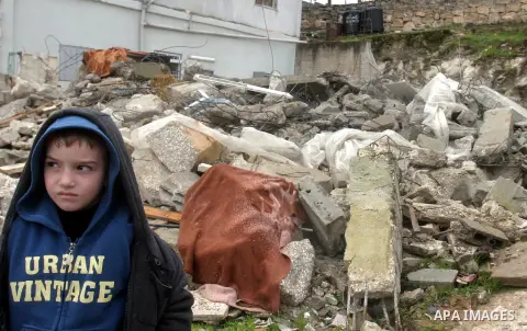A Palestinian boy from Jabari family sits on the rubble of their house after it was demolished by Jerusalem municipality workers in the mostly Arab east Jerusalem neighborhood of al-Tur on December 11, 2012. Palestinian...