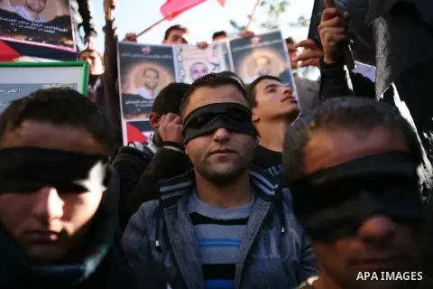 Protesters hold portraits of Samer Issawi and Ayman Sharwanah, Palestinian prisoners held in Israeli jails and on hunger strike, during a solidarity protest in the West Bank city of Hebron, December 12, 2012. Demonstrato...
