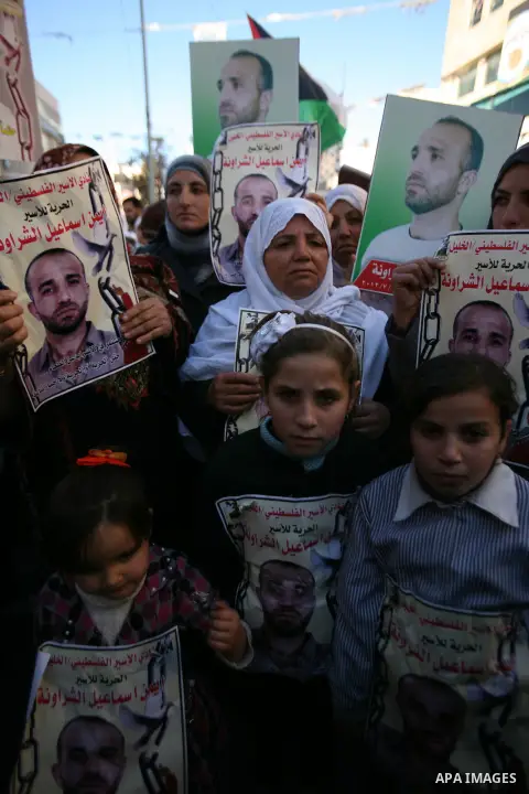 Protesters hold portraits of Samer Issawi and Ayman Sharwanah, Palestinian prisoners held in Israeli jails and on hunger strike, during a solidarity protest in the West Bank city of Hebron, December 12, 2012. Demonstrato...