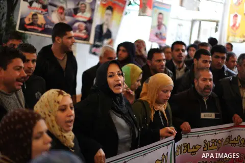 Supporters of Democratic Front for the Liberation of Palestine (DFLP) hold flags and portraits of Palestinian prisoners held in Israeli jails during a rally calling for their release, in Gaza city on Dec. 13, 2012. Photo...