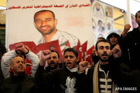 Supporters of Democratic Front for the Liberation of Palestine (DFLP) hold flags and portraits of Palestinian prisoners held in Israeli jails during a rally calling for their release, in Gaza city on Dec. 13, 2012. Photo...