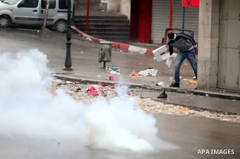 A Palestinian protester covers from tear gas shoot by Israeli soldiers during clashes in the West Bank city of Hebron, 13 December 2012. The clashes broke out before the funeral of Palestinian teenager Mohammed Ziad Sala...