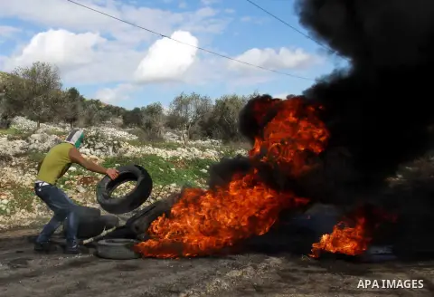 A Palestinian protester burns tyres as clashes broke out with Israeli soldiers during a demonstration against the expropriation of Palestinian land by Israel in the village of Kfar Qaddum, near the occupied West Bank cit...