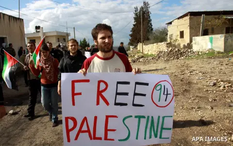 Palestinian protesters hold a placard ''free palestine'' during a demonstration against the expropriation of Palestinian land by Israel in the village of Kfar Qaddum, near the occupied West Bank city of Nablus, on Decemb...