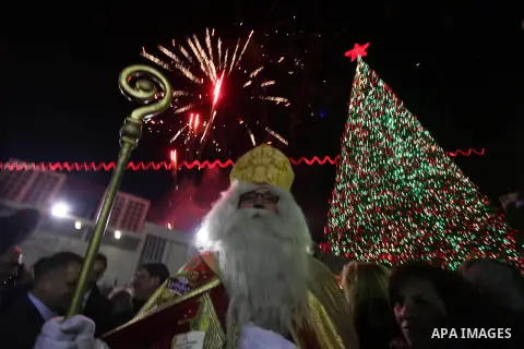Palestinians celebrate the lighting of the Christmas tree in Manger Square, outside the Church of the Nativity, in the West Bank biblical town of Bethlehem, the traditional birthplace of Jesus as preparations for Christm...