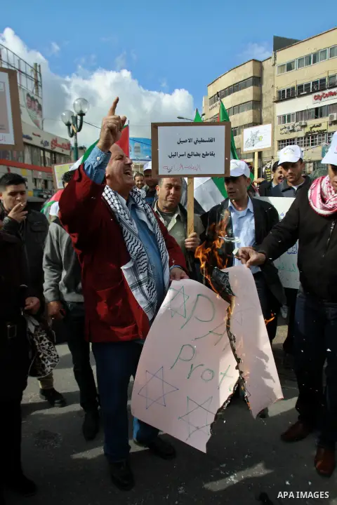 Palestinians burn a placard reading "Paris Protocol" and bearing the Star of David during a protest against the Paris Protocol and the Oslo Agreement, both key accords which govern economic ties between Palestinians and...