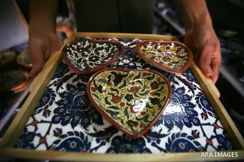 A Palestinian man displays plates made from ceramic and painted by using traditional skills in the West Bank city of Hebron on 16 December, 2012. Palestinian ceramics are produced at traditional family-owned factories in...