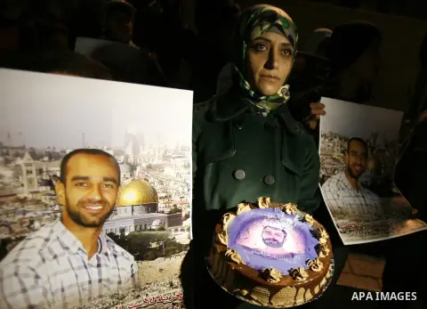 Palestinian protesters hold portraits of Samer Issawi, a Palestinian prisoner held in an Israeli jail and on a hunger strike since August 1, during a demonstration marking his birthday outside Damascus gate, in the old c...