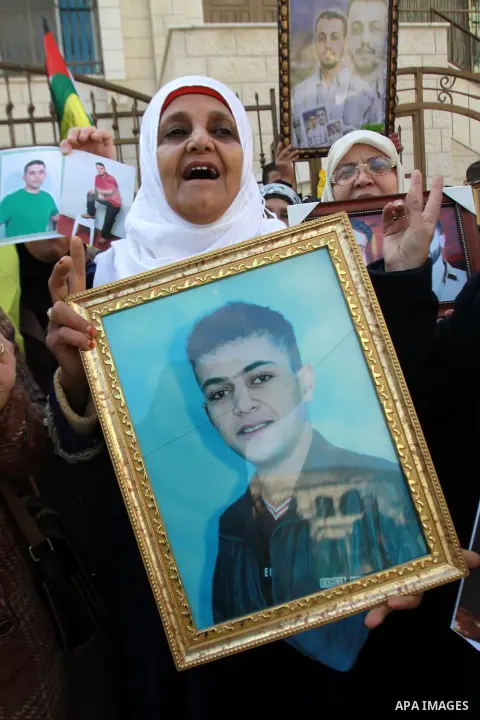 Palestinians hold pictures of their prisoner relatives in Israeli jails as they gather in a weekly activity calling for their liberty at the Red Cross headquarters in the West Bank city of Nablus on December 17, 2012. Ph...