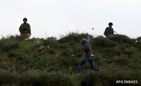 A masked Palestinian throws stones during clashes with Jewish settlers, not pictured, outside the West Bank village of Madama and the Jewish settlement of Yitzhar, near Nablus, Dec. 17, 2012. Photo by Nedal Eshtayah