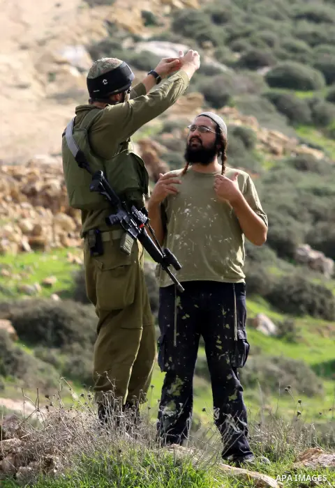 An Israeli soldier speaks with a Jewish settler during clashes with Palestinians, not seen, outside the West Bank village of Madama and the Jewish settlement of Yitzhar, near Nablus, Dec. 17, 2012. Photo by Nedal Eshtaya...