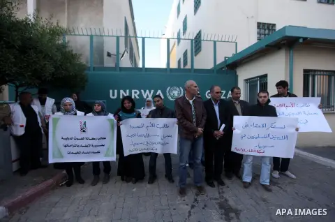 Palestinians hold placards during a protest in solidarity with Palestinian in al-Yarmouk refugee camp in Syria in In front of the United Nations headquarters in Gaza City on 18 December 2012. Pro-rebel sources reported t...