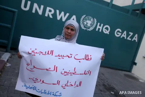 A Palestinian woman holds placards during a protest in solidarity with Palestinian in al-Yarmouk refugee camp in Syria in In front of the United Nations headquarters in Gaza City on 18 December 2012. Pro-rebel sources re...
