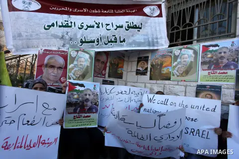 Palestinians hold pictures of prisoners held in Israeli jails during a sit-in outside the Red Crescent offices near the West Bank city of Ramallah on December 17, 2012. in solidarity with hunger-striking detainees held b...