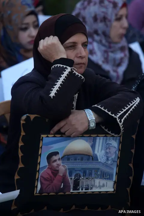 Palestinians hold pictures of prisoners held in Israeli jails during a sit-in outside the Red Crescent offices near the West Bank city of Ramallah on December 17, 2012. in solidarity with hunger-striking detainees held b...