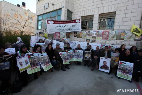 Palestinians hold pictures of prisoners held in Israeli jails during a sit-in outside the Red Crescent offices near the West Bank city of Ramallah on December 17, 2012. in solidarity with hunger-striking detainees held b...