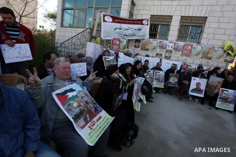 Palestinians hold pictures of prisoners held in Israeli jails during a sit-in outside the Red Crescent offices near the West Bank city of Ramallah on December 17, 2012. in solidarity with hunger-striking detainees held b...