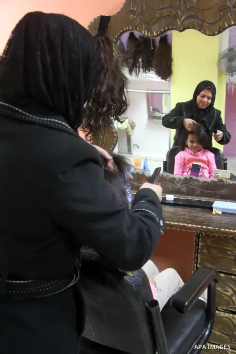 A Palestinian woman, Samar Bulbul prepares her daughter at her home in Gaza city on Dec. 18,2012. Bulbul lost hearing after an Israeli airstrike targeted two Palestinian militants' car in Gaza city in December 2011. Phot...