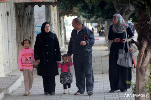 A Palestinian woman, Samar Bulbul walks with her family at a street in Gaza city on Dec. 18,2012. Bulbul lost hearing after an Israeli airstrike targeted two Palestinian militants' car in Gaza city in December 2011. Phot...