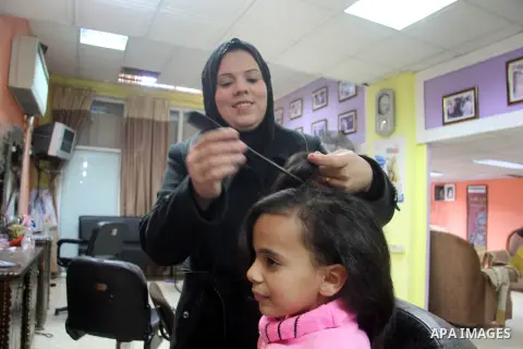 A Palestinian woman, Samar Bulbul prepares her daughter at her home in Gaza city on Dec. 18,2012. Bulbul lost hearing after an Israeli airstrike targeted two Palestinian militants' car in Gaza city in December 2011. Phot...