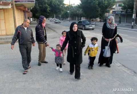A Palestinian woman, Samar Bulbul walks with her family at a street in Gaza city on Dec. 18,2012. Bulbul lost hearing after an Israeli airstrike targeted two Palestinian militants' car in Gaza city in December 2011. Phot...