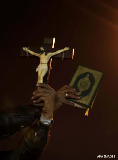A man holds a copy of the Koran and a cross as she shouts slogans during a demonstration against Egypt's President Mohamed Mursi in front of the presidential palace in Cairo December 18, 2012. Opponents of Mursi staged p...