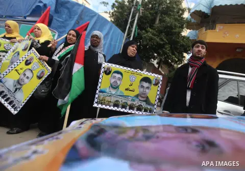 Palestinians hold pictures of prisoners held in the Israeli jails during a rally in Gaza city on December 19, 2012. in solidarity with hunger-striking detainees held by Israel to demand their release from detention witho...