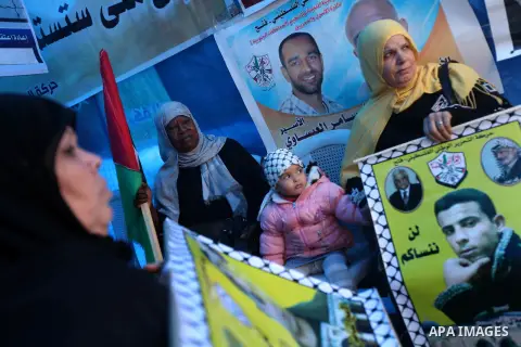 Palestinians hold pictures of prisoners held in the Israeli jails during a rally in Gaza city on December 19, 2012. in solidarity with hunger-striking detainees held by Israel to demand their release from detention witho...