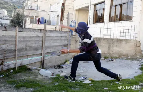 A masked Palestinian youth throws stones at Israeli soldiers during clashes in the Arab Jerusalem neighbourhood of Issawiya after a demonstration in solidarity with Palestinian prisoner Samer Issawi, held in an Israeli j...