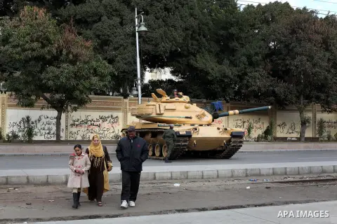 Egyptians walk pass the wire barricade as Egyptian army soldiers and tanks guard the presidental palace in Cairo December 19, 2012. Opponents of Egyptian President Mohamed Mursi staged protests in Cairo on Tuesday agains...